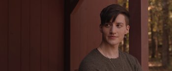 Movie still from “They/Them” (2022), directed by John Logan – A person with short hair is standing outside; Close Up shot, Over the shoulder angle