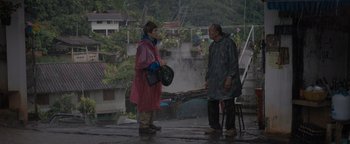 Movie still from “Thirteen Lives” (2022), directed by Ron Howard – A man and a woman are standing outside in the rain; Wide shot, Over the shoulder angle