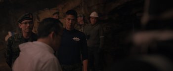 Movie still from “Thirteen Lives” (2022), directed by Ron Howard – A group of men standing around in a cave; Medium shot, Over the shoulder angle
