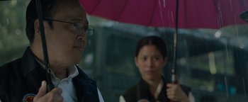 Movie still from “Thirteen Lives” (2022), directed by Ron Howard – A man and a woman holding an open umbrella; Close Up shot, Over the shoulder angle