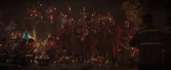 Movie still from “Thirteen Lives” (2022), directed by Ron Howard – A group of people in red robes standing in front of candles; Wide shot, High angle