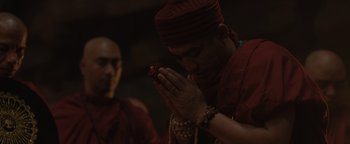 Movie still from “Thirteen Lives” (2022), directed by Ron Howard – A man in a red hat is holding his hands in prayer; Close Up shot, Low angle