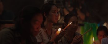 Movie still from “Thirteen Lives” (2022), directed by Ron Howard – A group of people holding candles in a dark room; Close Up shot, Low angle