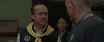 Movie still from “Thirteen Lives” (2022), directed by Ron Howard – A group of people standing next to each other in a room; Close Up shot, Over the shoulder angle