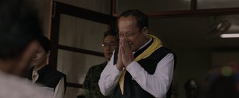 Movie still from “Thirteen Lives” (2022), directed by Ron Howard – A man with a yellow neck scarf is praying; Close Up shot, High angle