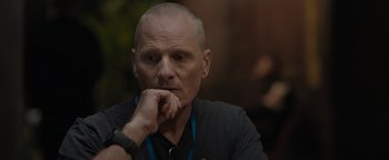 Movie still from “Thirteen Lives” (2022), directed by Ron Howard – A man with a beard is sitting with his hand under his chin; Close Up shot, Over the shoulder angle