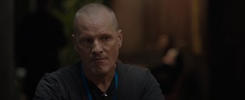 Movie still from “Thirteen Lives” (2022), directed by Ron Howard – A man with a shaved head is sitting in a room; Close Up shot, Over the shoulder angle