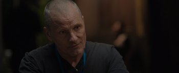 Movie still from “Thirteen Lives” (2022), directed by Ron Howard – A man with a shaved head is sitting in a room; Close Up shot, Over the shoulder angle