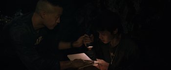 Movie still from “Thirteen Lives” (2022), directed by Ron Howard – Two people are looking at a book in the dark; Medium shot, High angle