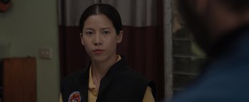 Movie still from “Thirteen Lives” (2022), directed by Ron Howard – A woman in a yellow shirt and a black vest; Close Up shot, Over the shoulder angle