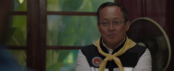 Movie still from “Thirteen Lives” (2022), directed by Ron Howard – A man with glasses and a yellow neckerchief around his neck; Close Up shot, Over the shoulder angle