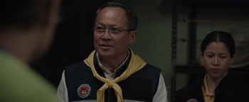 Movie still from “Thirteen Lives” (2022), directed by Ron Howard – A man wearing a vest and a yellow neck tie; Close Up shot, Over the shoulder angle