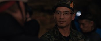 Movie still from “Thirteen Lives” (2022), directed by Ron Howard – A man wearing a hat and glasses in the dark; Close Up shot, Over the shoulder angle