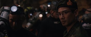 Movie still from “Thirteen Lives” (2022), directed by Ron Howard – A group of people standing next to each other in the dark; Close Up shot, Over the shoulder angle