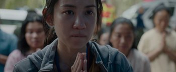 Movie still from “Thirteen Lives” (2022), directed by Ron Howard – A woman with her hands clasped in front of her face; Close Up shot, High angle