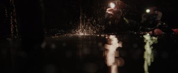 Movie still from “Thirteen Lives” (2022), directed by Ron Howard – A person is holding a flashlight over a body of water at night; Extreme Close Up shot, Overhead angle