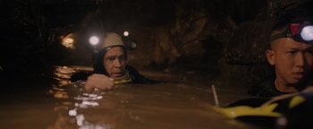 Movie still from “Thirteen Lives” (2022), directed by Ron Howard – A man in a hard hat is in a cave; Medium shot, High angle