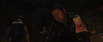 Movie still from “Thirteen Lives” (2022), directed by Ron Howard – A man in military fatigues is looking at the camera; Close Up shot, Over the shoulder angle