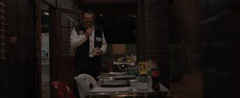 Movie still from “Thirteen Lives” (2022), directed by Ron Howard – A man standing in front of a dining table; Medium shot, Over the shoulder angle