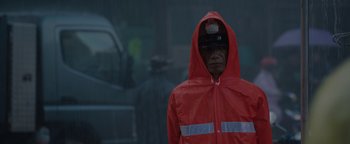 Movie still from “Thirteen Lives” (2022), directed by Ron Howard – A man wearing a red rain jacket and a hat; Close Up shot, Over the shoulder angle