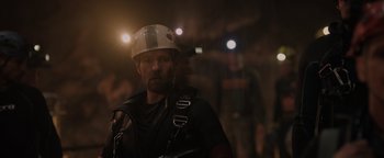 Movie still from “Thirteen Lives” (2022), directed by Ron Howard – A man with a helmet on in the dark; Close Up shot, Over the shoulder angle