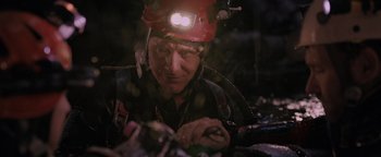 Movie still from “Thirteen Lives” (2022), directed by Ron Howard – A man wearing a hard hat with a light on his head; Close Up shot, Low angle