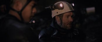 Movie still from “Thirteen Lives” (2022), directed by Ron Howard – A man wearing a helmet while standing in the water; Close Up shot, Over the shoulder angle