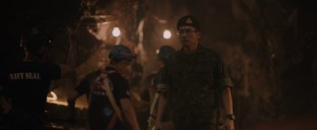 Movie still from “Thirteen Lives” (2022), directed by Ron Howard – A man in military fatigues walking down a street; Medium shot, Over the shoulder angle