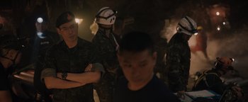 Movie still from “Thirteen Lives” (2022), directed by Ron Howard – A group of people standing next to each other in a cave; Medium shot, Over the shoulder angle