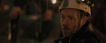 Movie still from “Thirteen Lives” (2022), directed by Ron Howard – A person wearing a hard hat; Close Up shot, Over the shoulder angle