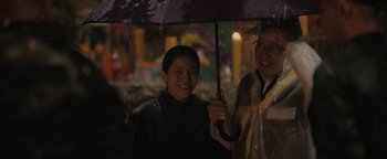 Movie still from “Thirteen Lives” (2022), directed by Ron Howard – Two people holding an umbrella in the rain; Close Up shot, Over the shoulder angle
