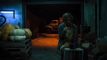 Movie still from “Escape Room” (2019), directed by Adam Robitel – A man sitting on the ground looking at a cell phone; Medium shot, Low angle