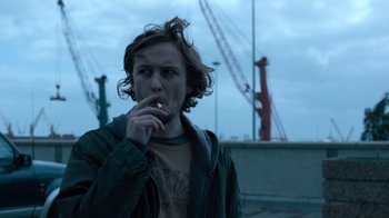 Movie still from “Escape Room” (2019), directed by Adam Robitel – A man smoking a cigarette while standing on a pier; Close Up shot, Low angle
