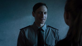 Movie still from “Escape Room” (2019), directed by Adam Robitel – A man in a uniform smiling for the camera; Close Up shot, Over the shoulder angle
