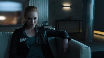 Movie still from “Escape Room” (2019), directed by Adam Robitel – A woman sitting on a couch in a room; Medium shot, Over the shoulder angle