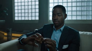 Movie still from “Escape Room” (2019), directed by Adam Robitel – A man in a suit holding a piece of food; Close Up shot, Over the shoulder angle