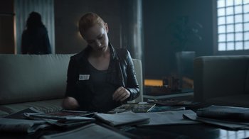 Movie still from “Escape Room” (2019), directed by Adam Robitel – A woman sitting at a table looking at papers; Medium shot, Over the shoulder angle