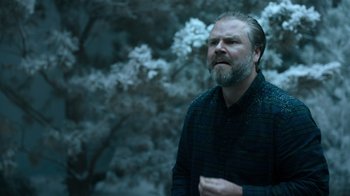 Movie still from “Escape Room” (2019), directed by Adam Robitel – A man with a goatee standing next to a tree; Close Up shot, Over the shoulder angle