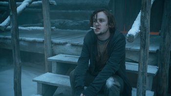 Movie still from “Escape Room” (2019), directed by Adam Robitel – A man sitting on steps with a cigarette in his mouth; Medium shot, Low angle