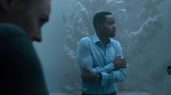 Movie still from “Escape Room” (2019), directed by Adam Robitel – A man in a blue dress shirt is standing with his arms crossed; Medium shot, Over the shoulder angle