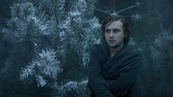 Movie still from “Escape Room” (2019), directed by Adam Robitel – A man sitting in front of a tree in a snowy forest; Medium shot, Low angle