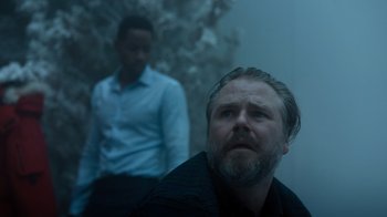 Movie still from “Escape Room” (2019), directed by Adam Robitel – A man sitting next to another man in a room; Medium shot, Low angle