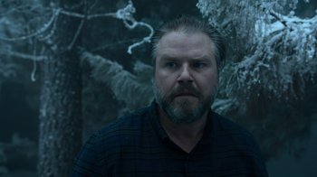 Movie still from “Escape Room” (2019), directed by Adam Robitel – A man with a goatee is standing in front of trees; Close Up shot, Low angle