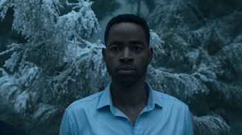 Movie still from “Escape Room” (2019), directed by Adam Robitel – A man in a blue dress shirt is standing in front of a tree; Close Up shot, Low angle