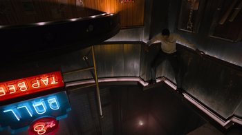 Movie still from “Escape Room” (2019), directed by Adam Robitel – A man leaning on a railing in a dark room; Wide shot, Overhead angle