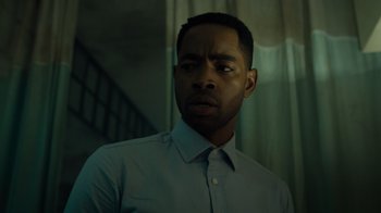 Movie still from “Escape Room” (2019), directed by Adam Robitel – A man standing in front of a staircase in a room; Close Up shot, Low angle