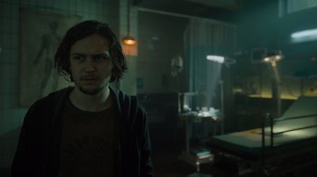 Movie still from “Escape Room” (2019), directed by Adam Robitel – A man standing in a dark room with a light on; Medium shot, Low angle