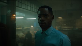 Movie still from “Escape Room” (2019), directed by Adam Robitel – A man standing in a room with a lot of lights in the background; Close Up shot, Low angle
