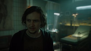 Movie still from “Escape Room” (2019), directed by Adam Robitel – A man with long dark hair standing in a room; Close Up shot, Low angle