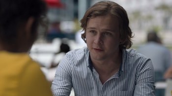 Movie still from “Escape Room” (2019), directed by Adam Robitel – A man with long brown hair wearing a blue and white striped shirt; Close Up shot, Over the shoulder angle